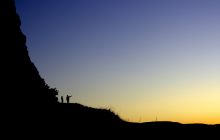 Silhouette of two figures on a hill
