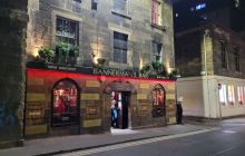 Street lights illuminate the first two floors of a stone building in Edinburgh's Cowgate with a redlit sign saying Bannerman's bar
