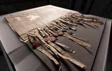 A worn and aged document with medieval seals strung flimsily from it is spread out in a display cabinet in low light. This is the Declaration of Arbroath
