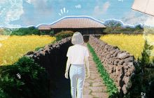 A traditional house is in the background, with a bright blue sky. The outline of a girl is shown walking towards it, down a country lane with fields either side.