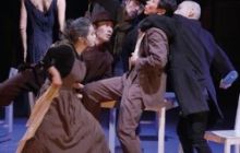 A group of dancers contort around a desk.