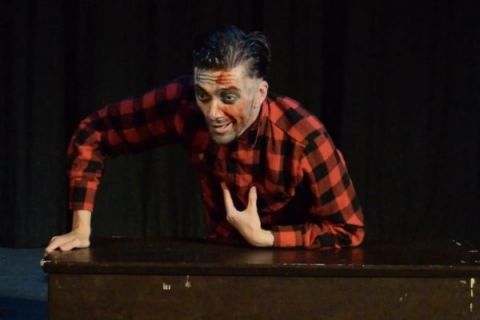 Simon Shaw as Ed Gein gestures with blood on his face