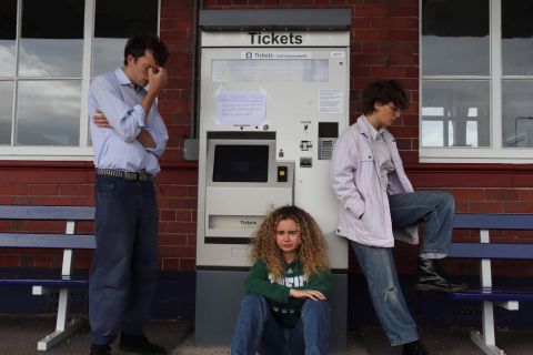 The cast at a railway station to dramatise a scene from No Time For Strangers