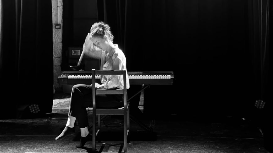 Actor Molly Hanly, pictured sitting sideways on a chair, backlit with light shining through.