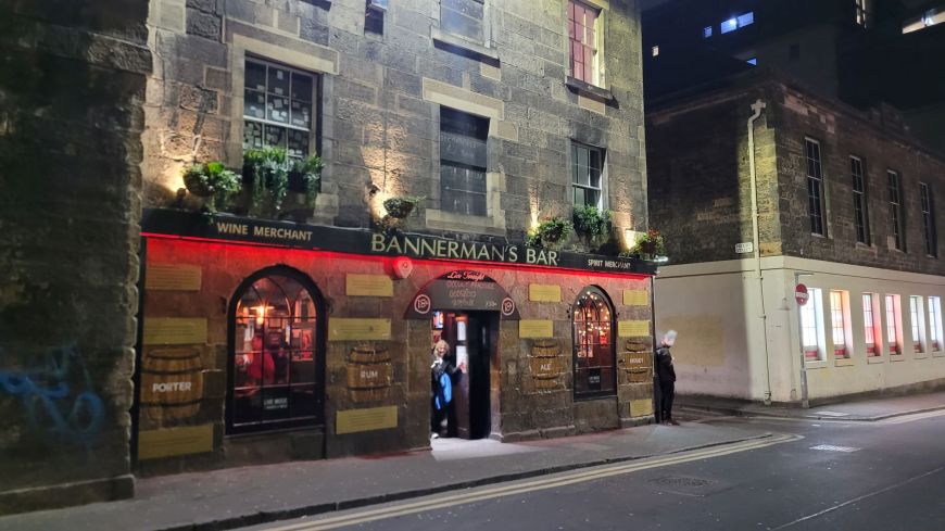 Street lights illuminate the first two floors of a stone building in Edinburgh's Cowgate with a redlit sign saying Bannerman's bar