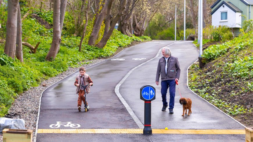 Young boy on scooter and man with his dog on Speirs Bruce Way pedestrian-bike path after opening