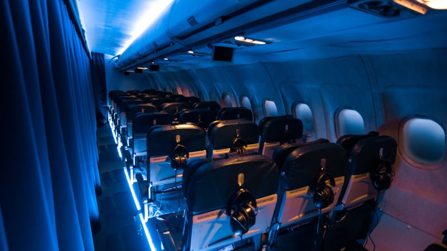 Moody blue lighting shows rows of seats in an airplane.