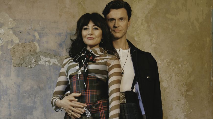 Stars Frances Ruffelle and Norman Bowman pictured in each others arms, looking at the camera. Ruffelle is wearing a rock-ish outfit; Bowman is wearing a leather jacket and a kilt.