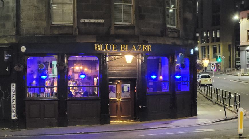 The Blue Blazer pub at nighttime with windows lit violet blue