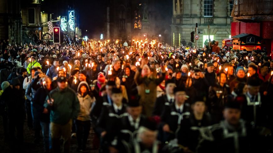 Pipe band and torchbearers on Royal Mile at Hogmanay Torchlight Procession