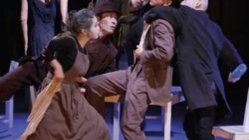 A group of dancers contort around a desk.