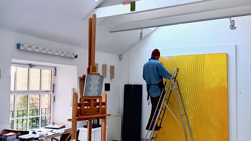 Artist in his studio working on a painting.