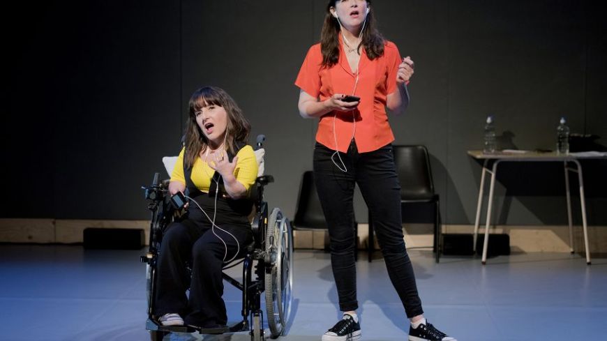 Lisa Hammond (left) and Rachael Spence (right) face the audience, dressed in dark trousers and bright coloured tops. They are contemplating.