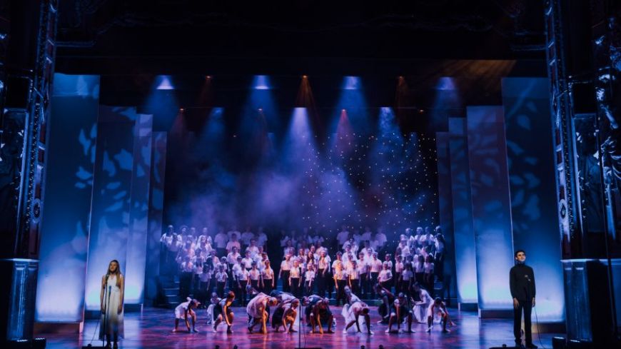 Soloists stand at either side of the stage, singing Falling Softly from Once. Dancers move in pair in the centre, beautifully covered in blue light.