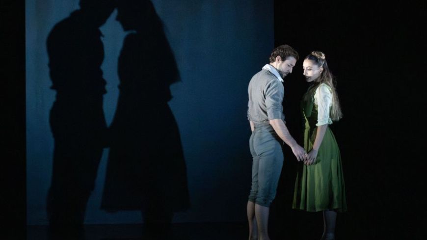 Bruno Micchiardi as John Proctor and Kayla-Maree Tarantolo as Abigail in The Crucible. John is tentatively reaching out to embrace Abigail's hand while their shadows are projected behind them.